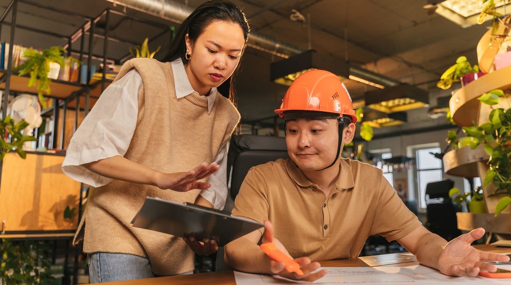 Consultant reviewing documents with an engineer in a hard hat, part of a gap analysis by an ISO consultant in Malaysia